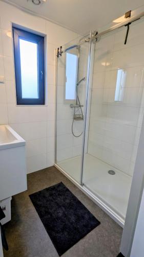 a bathroom with a shower and a sink and a window at Maison du Lac in Lathum