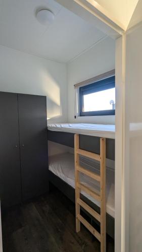 a small room with a bunk bed and a window at Maison du Lac in Lathum