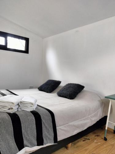 a bedroom with a bed with black and white pillows at Minicasas cerca del rio Los Reartes in Villa Ciudad Parque