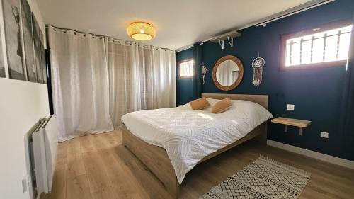 Schlafzimmer mit einem Bett mit blauen Wänden und einem Spiegel in der Unterkunft Maison familiale rénovée au calme a bon encontre in Bon-Encontre
