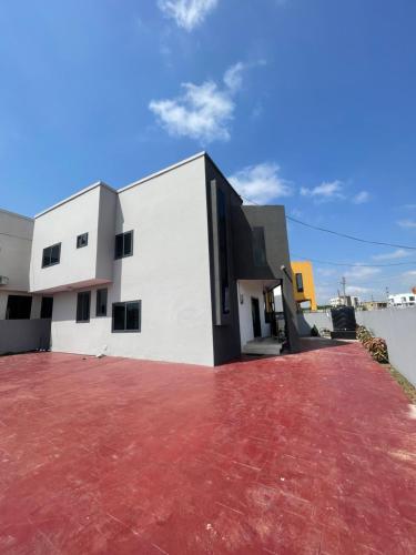 a white building with a red driveway at Noahjoelestate in Accra
