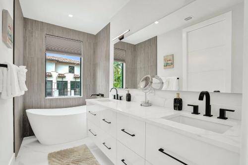 ein weißes Badezimmer mit Waschbecken und Spiegel in der Unterkunft New 4BR w Pool Walk to Las Olas 5mins to Beach in Fort Lauderdale