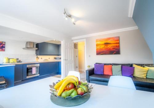 a kitchen and living room with a bowl of fruit on a table at Brunswick Fab Pad By My Getaways in Brighton & Hove