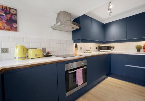 a kitchen with blue cabinets and a stove at Brunswick Fab Pad By My Getaways in Brighton & Hove