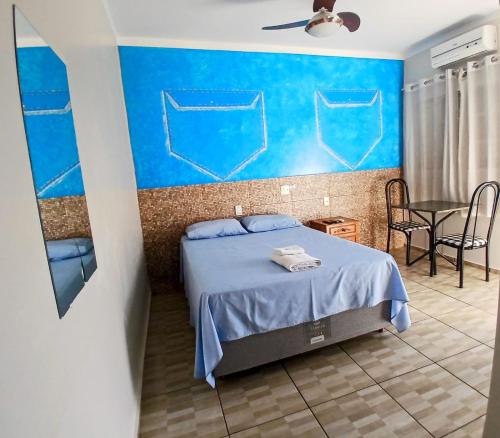 a bedroom with a bed and a blue wall at Raízes Hotel in Cajobi