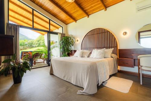 a bedroom with a bed and a desk and a window at Villas Jawara ! Un Volcán en su Jardín ! in Fortuna