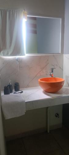 an orange sink on a counter in a bathroom at Cacho's house in Junín