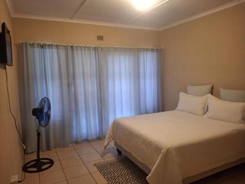 谢普斯敦港The Royal Holiday Home的一间卧室配有一张床和一个带风扇的窗户。