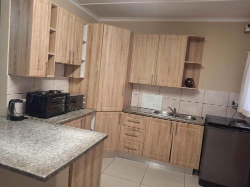 谢普斯敦港The Royal Holiday Home的配有木质橱柜、水槽和微波炉的厨房