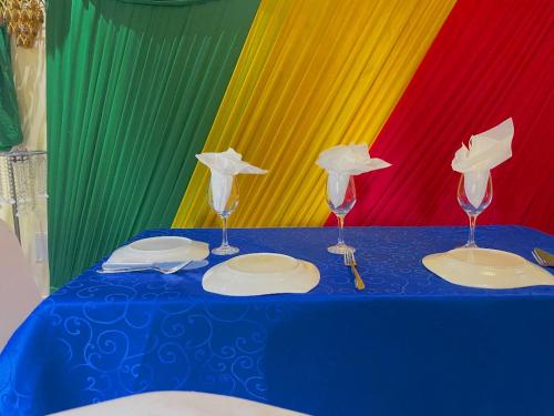 Una mesa con dos copas de vino y platos delante de una bandera. en Essérè Mabia hôtel E-M, en Brazzaville