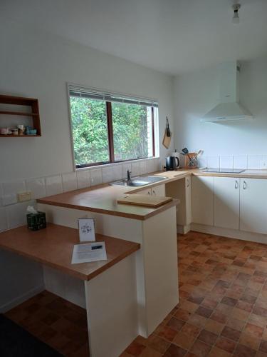 a kitchen with white cabinets and a sink and a window at House in Restful Setting in Whangarei