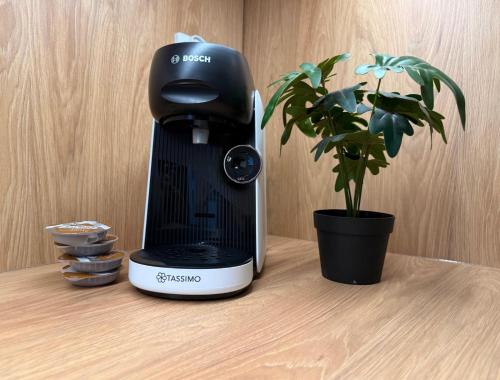 una macchinetta del caffè seduta su un tavolo accanto a una pianta di Old Town Bulwar Apartment a Elblag