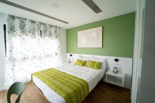 a bedroom with a bed with green walls and a window at GREEN STUDIO - Apt 003 Aconchegante e Moderno in Tarrafal