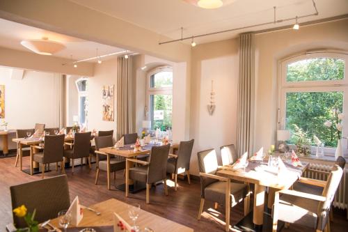 a dining room with tables and chairs and windows at Hotel Zur-Borke in Neuenrade