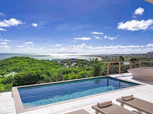 a swimming pool with a view of the ocean at Villa Atao, sublime view of Orient Bay and the islands in Cul de Sac