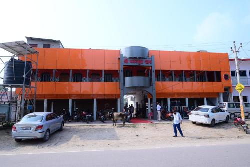 an orange building with cars parked in front of it at Pawansut Dham in Naimishāranya