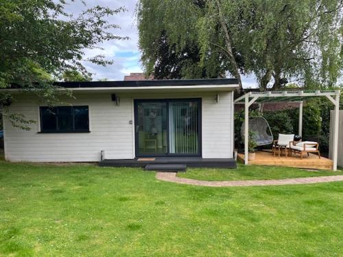 a small white house with a porch and a patio at Independent garden studio - sleeps max 3. in Derby