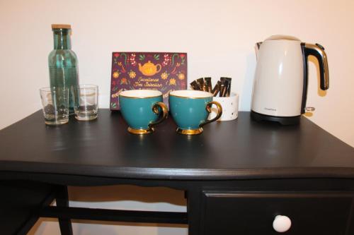 a table with two coffee cups and a bottle of wine at Chambre d'hôtes cosy à la campagne in Bourg-des-Comptes