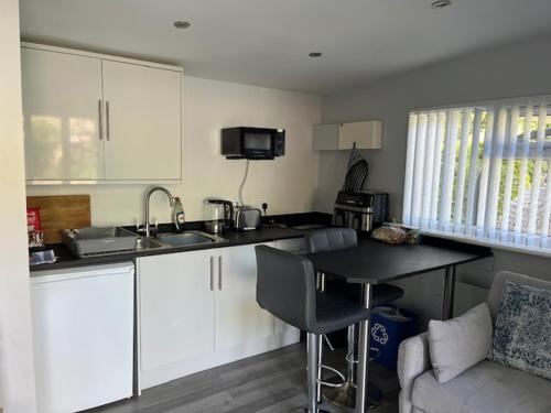 eine Küche mit weißen Schränken, einem Tisch und einer Couch in der Unterkunft Independent garden studio - sleeps max 3. in Derby