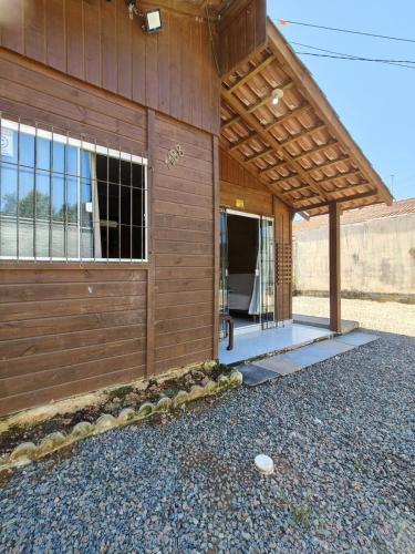 a wooden building with a door and some rocks at Casa Praia in Piçarras