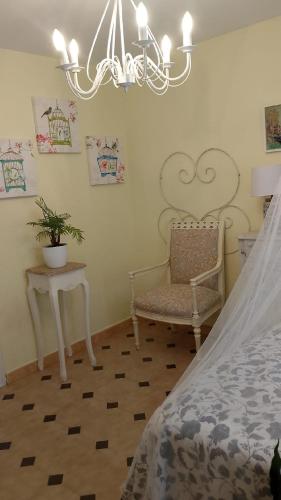 a bedroom with a bed and a chair and a chandelier at Flor de Loto in Candeleda