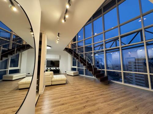 Exclusive Penthouse And SPA في ريغا: غرفة معيشة بها درج ونوافذ كبيرة