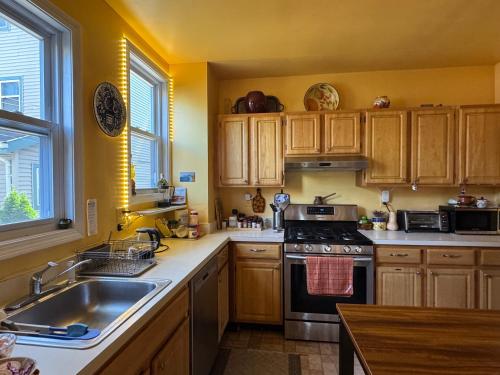 a kitchen with wooden cabinets and a stove top oven at Beautiful Victorian house, Room in Boston
