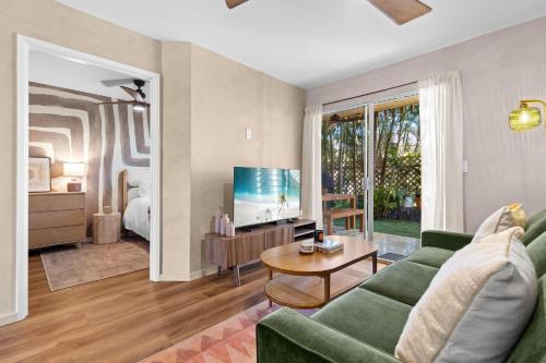 a living room with a green couch and a tv at Casa Aloha Designer Condo w Oceanfront Pool in Kailua-Kona