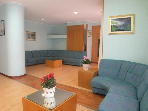 una sala de estar con sofás azules y flores en una mesa. en Hotel La Pergola, en Rionero in Vulture