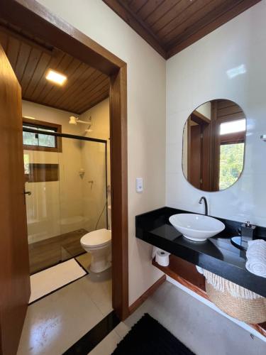 a bathroom with a sink and a toilet and a mirror at Sítio Rancho Mineiro in Domingos Martins
