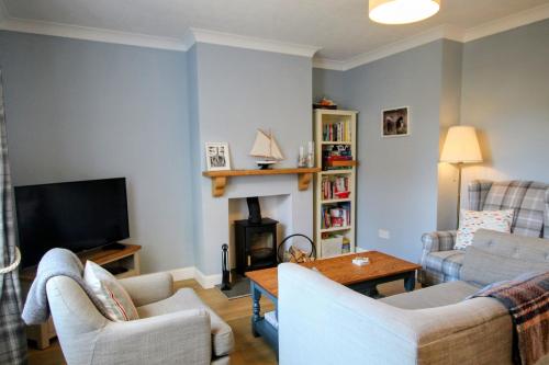 a living room with two couches and a television at Nina's Cottage - Southwold in Southwold