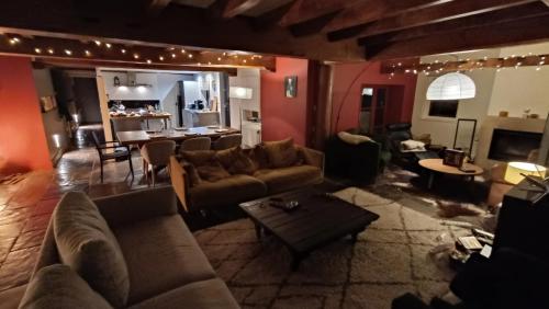 ein Wohnzimmer mit Couch und Tisch und eine Küche in der Unterkunft ferme de caractère avec piscine et cheminée in Sainghin-en-Mélantois