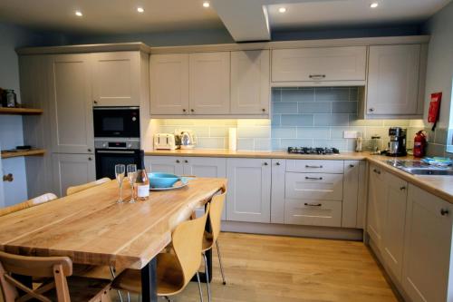 a kitchen with white cabinets and a wooden table at Nina's Cottage - Southwold in Southwold