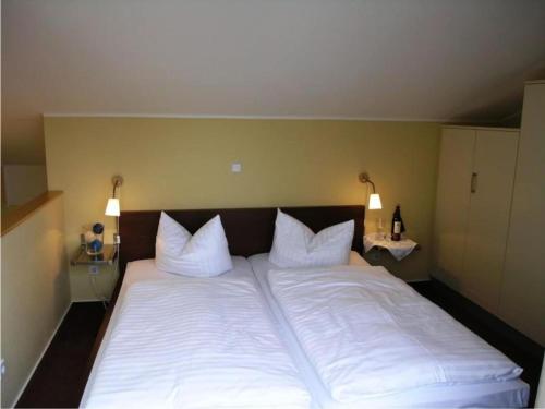 een groot bed met witte lakens en kussens bij elegant eingerichtete Ferienwohnung in Granzow