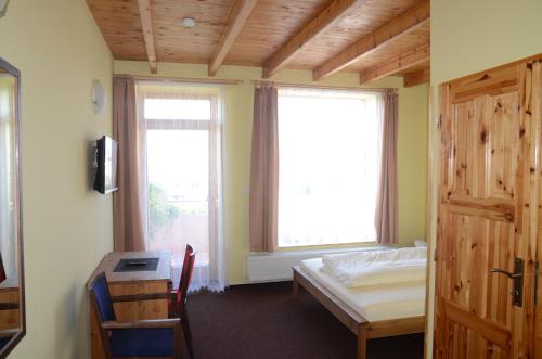 a bedroom with a bed and a desk and two windows at Penzion Folbr in Dlouhá Lhota
