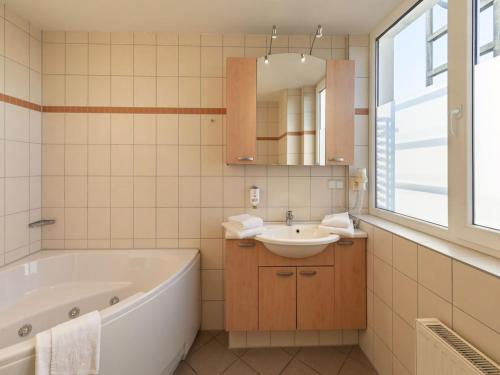 a bathroom with a tub and a sink and a mirror at elegant eingerichtete Ferienwohnung in Granzow