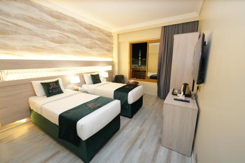 a hotel room with two beds and a television at Rose Holiday i3 روز هوليداي in Medina
