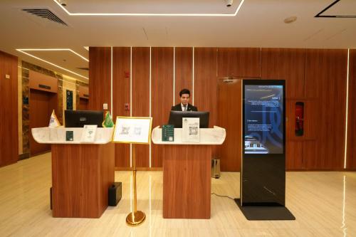 a man sitting at a desk in an office with a laptop at Rose Holiday i3 روز هوليداي in Al Madinah