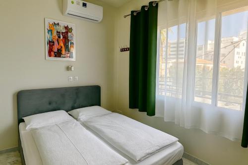 łóżko w sypialni z zieloną zasłoną i oknem w obiekcie Smart Comfort RoomN2 with Private Bathroom in best Location Beach 250m w mieście Limassol