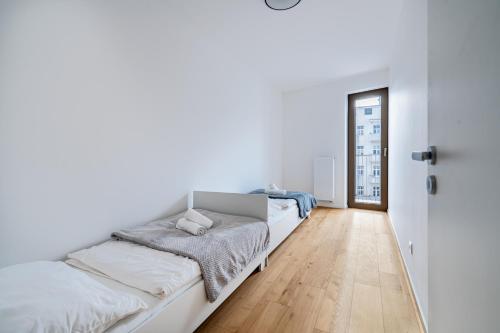 deux lits dans une chambre aux murs blancs et au parquet dans l'établissement Baker Balcony Apartment, à Brno