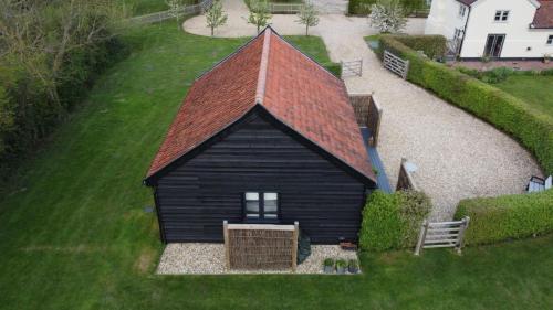 a small black building with a red roof at Rhubarb Barn bedroom only in Diss
