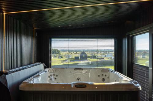 a bath tub in a room with a large window at Black barn in Rusinowo