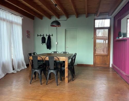 a dining room with a wooden table and black chairs at Casa Sol de Enero in Malargüe