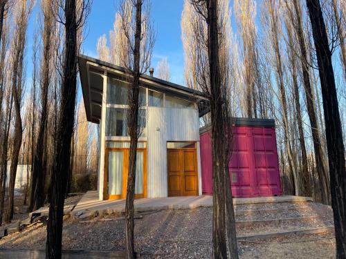 a house with a red garage in a forest at Casa Sol de Enero in Malargüe
