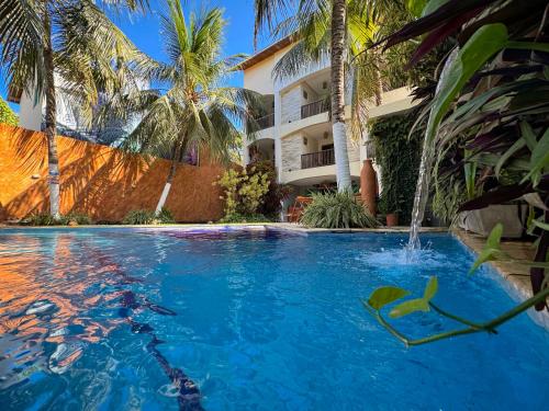 a swimming pool with a water fountain in front of a building at Pousada Unaí in Porto De Galinhas