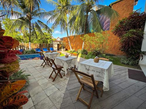 a patio with tables and chairs and palm trees at Pousada Unaí in Porto De Galinhas