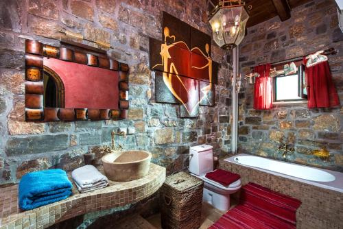 La salle de bains en pierre est pourvue d'une baignoire, d'un lavabo et de toilettes. dans l'établissement Villa Belladonna, à Pómbia