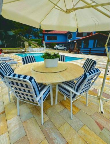 a wooden table with two chairs and an umbrella at Teresopolis casa ampla em clube com piscina in Teresópolis