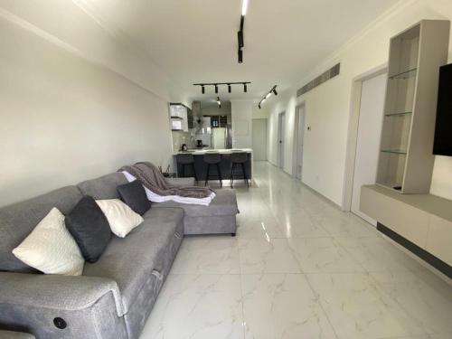a living room with a gray couch and a kitchen at Apartamento Exclusivo Av Principal LECHERIA in El Morro de Barcelona