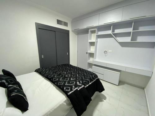 a bedroom with a bed with a black blanket on it at Apartamento Exclusivo Av Principal LECHERIA in El Morro de Barcelona